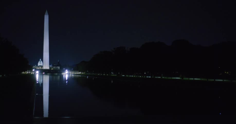 The washington monument at night lit up near water