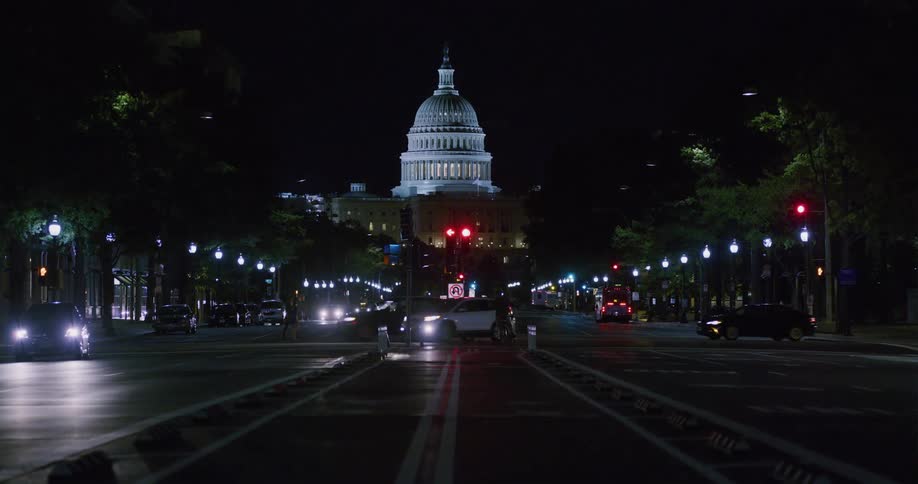 Cars are driving through a city during the night time