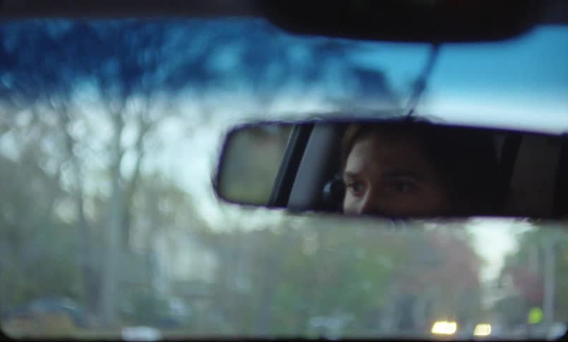 A woman is driving a car through a neighborhood