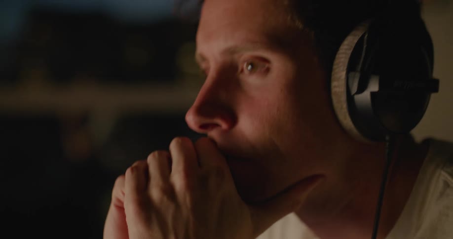 A man is smiling and wearing headphones indoors