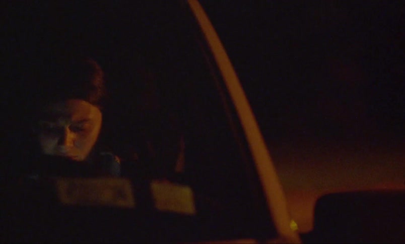 A woman sitting in her car at night