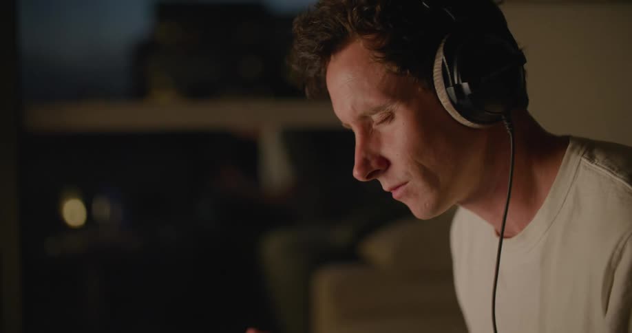 Musician follows the rhythm while listening to music on earphones while sitting on the couch at home