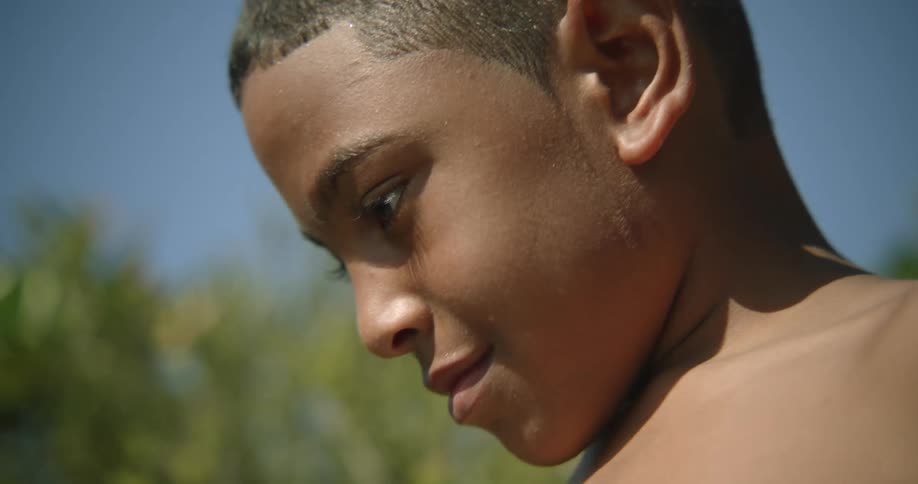 Boy smiles slightly while standing outdoors