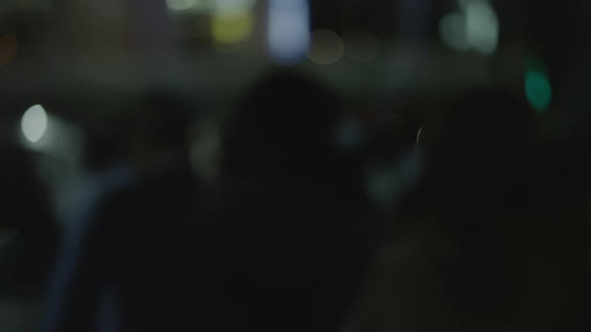 Out of focus footage of people walking on the city streets at night