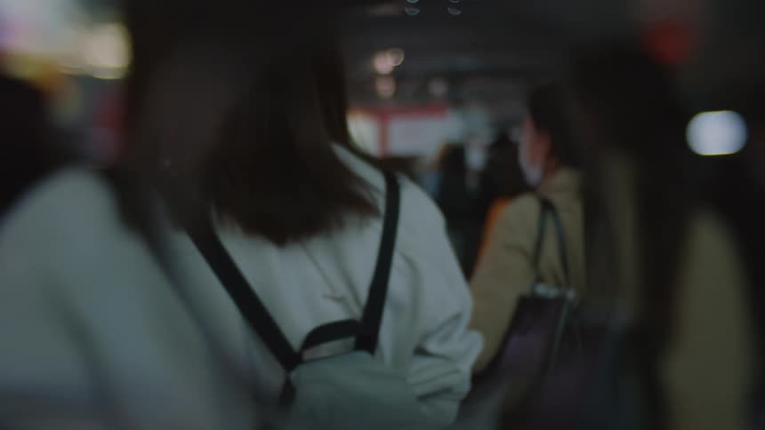 A crowd of people are walking through a city during the night