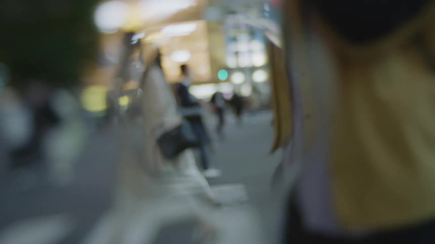 A crowd of pedestrians walk across a large intersection in a city at night