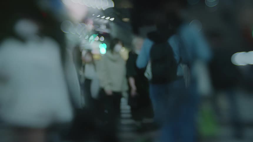A crowd of people are walking the city streets at night