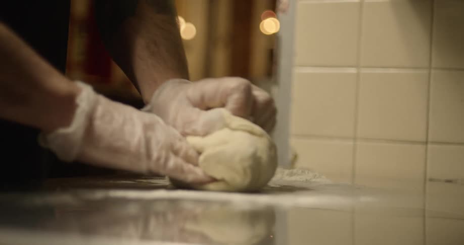 A man kneads dough in a restaurant kitchen