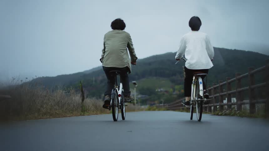 Couple driving bicycles on a rural road at daytime slowly coming into focus