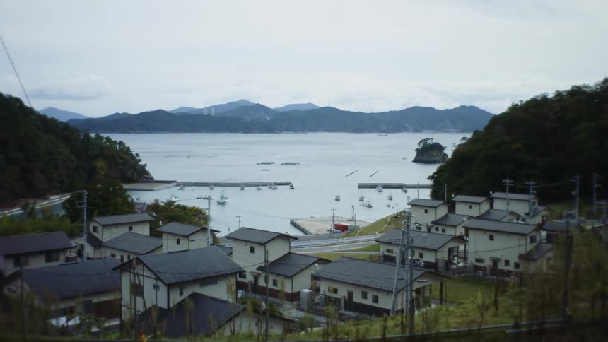 Houses on the shore with boats in the water and a mountain range across the water