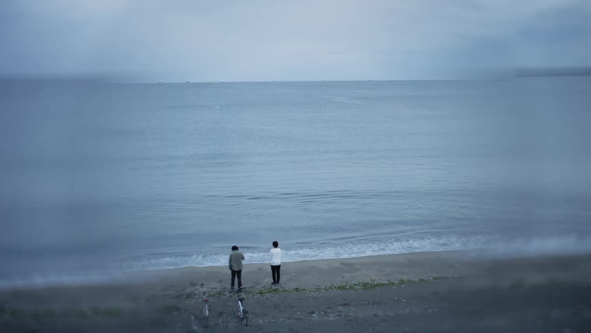 Two people are standing by the ocean coast