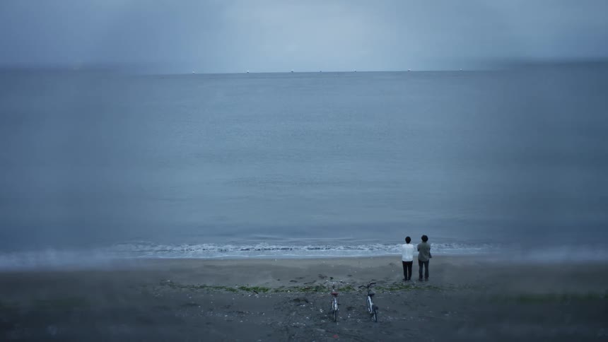 Two people watch the ocean together