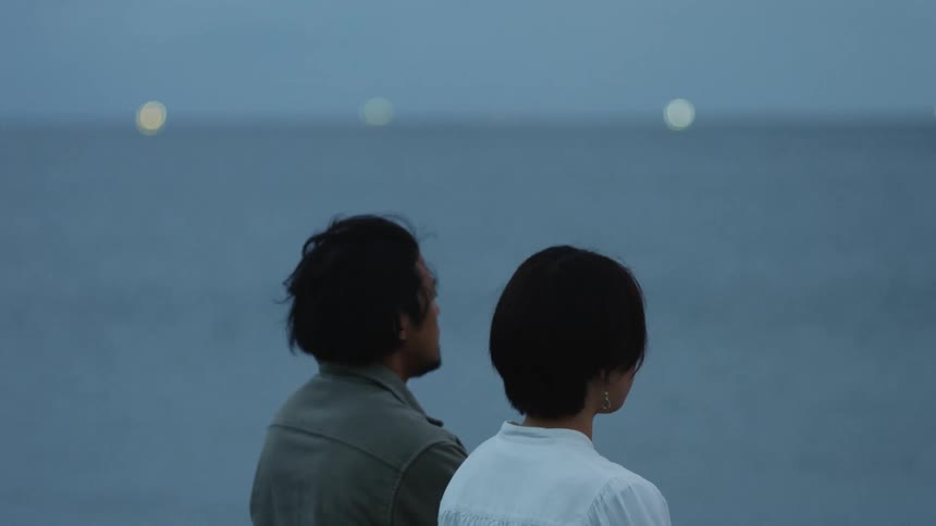 Man and woman are sitting by the ocean coast together