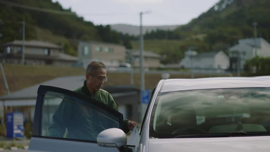 An older man is walking inside of his car after shopping
