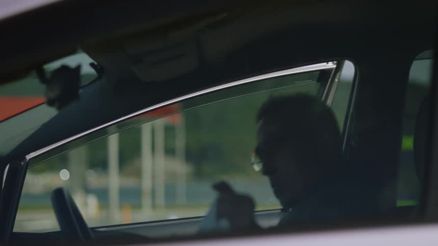 A person is walking and sits down in his car