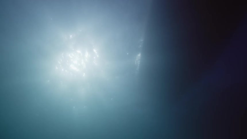 Underwater footage of sunlight shining on the surface near a boat