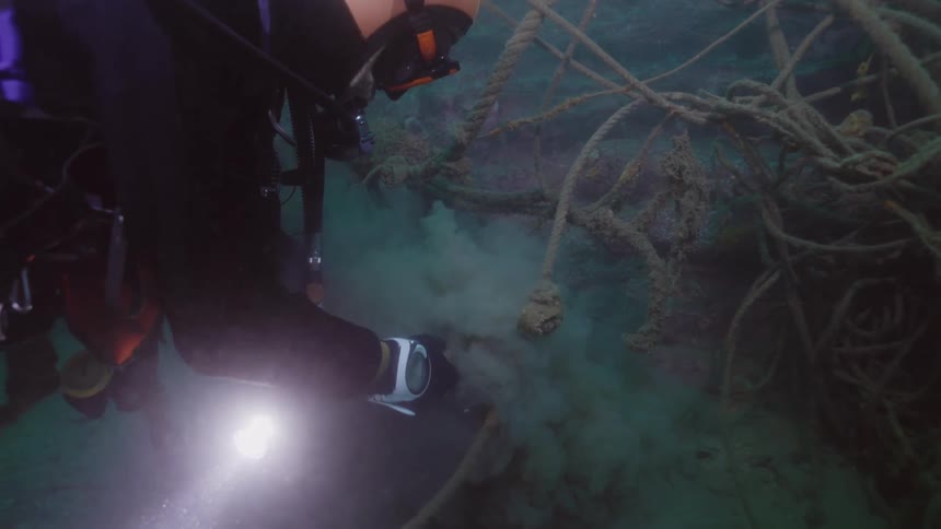 Scuba diver digs an object at the bottom of the ocean
