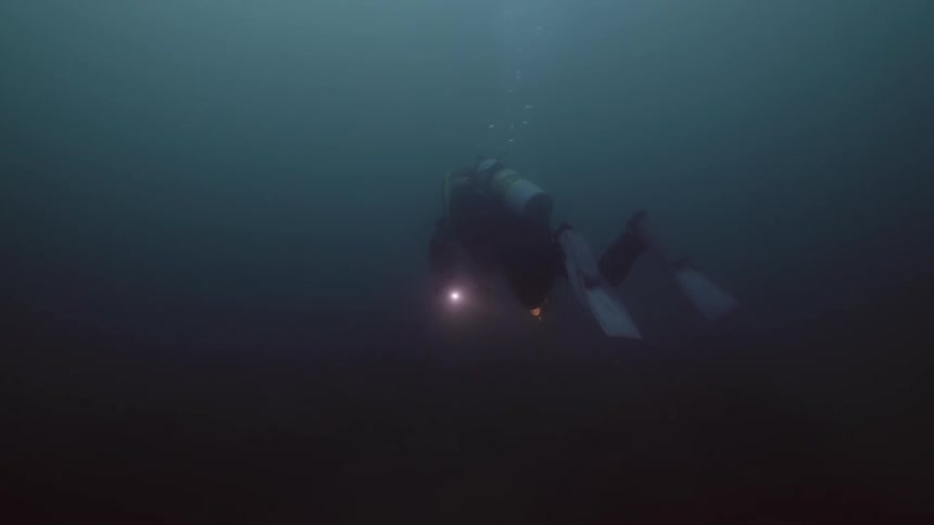 Scuba diver wearing diver skin flippers and tank swims underwater