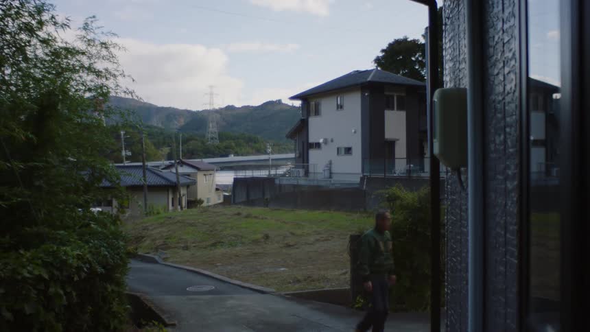Man walking on a road in the neighborhood enters a property
