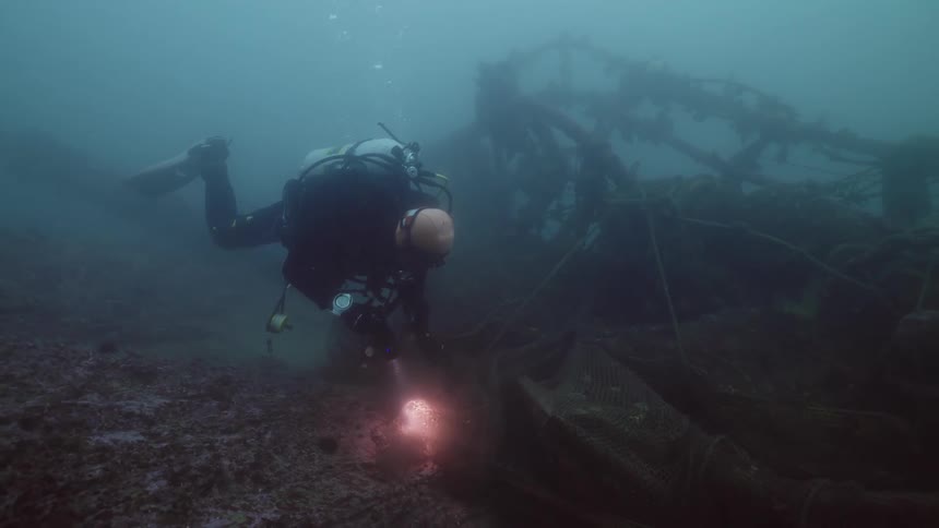 A man diving to a shipwreck in the bottom of the ocean