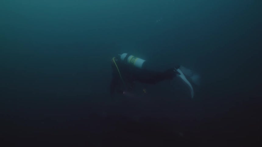 Scuba diver wearing diver skin flippers and tank swims underwater