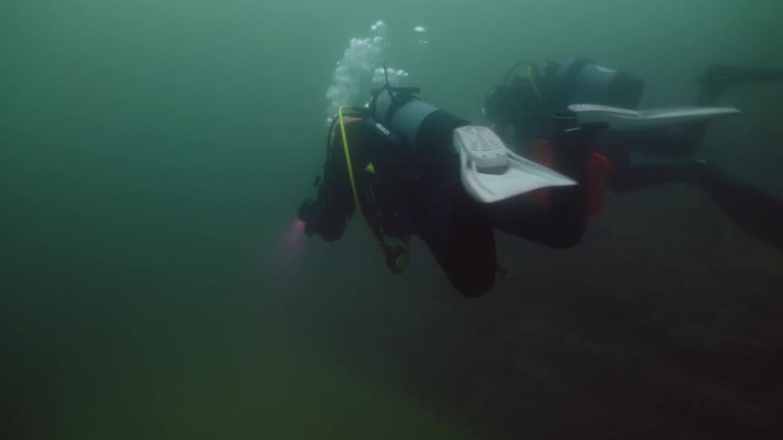 Two divers are searching underwater