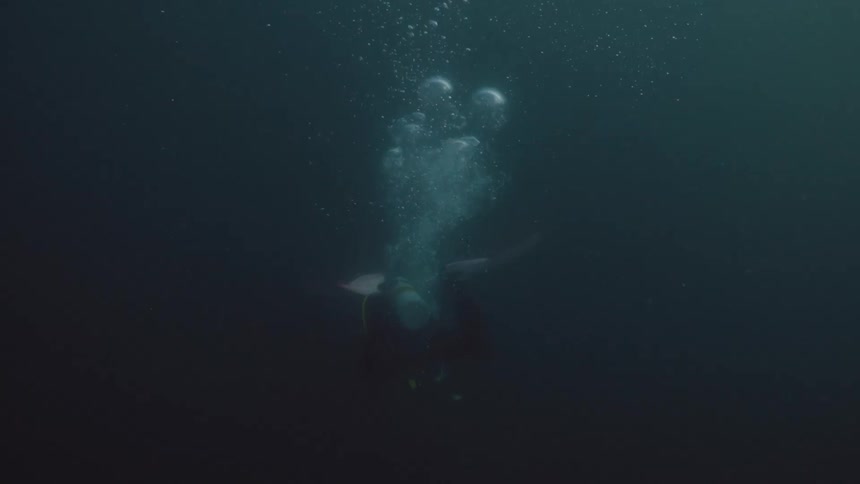 Scuba diver in wetsuit flippers swims underwater