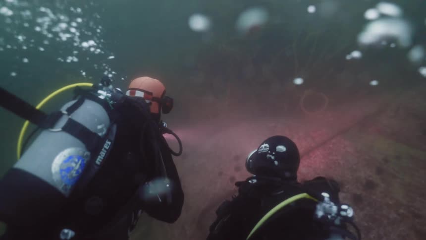 Two people are scuba diving in the ocean water