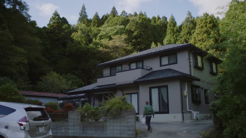 A man is walking inside of his house in the middle of the day