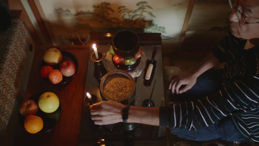 A man kneeling and lighting candles on a low table