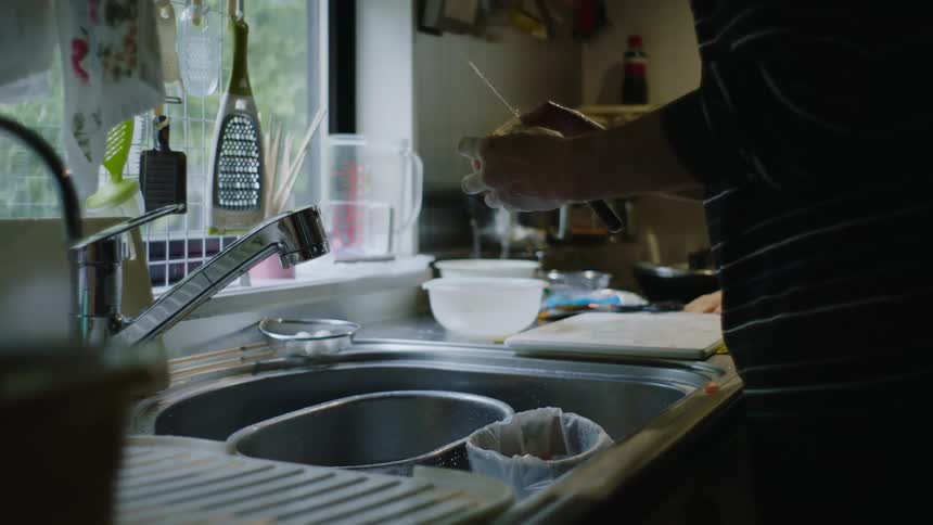 A person is cutting vegetables in their kitchen sink