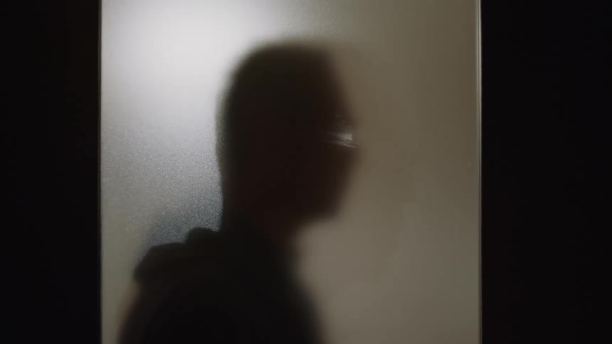 A silhouette of a man standing near a window