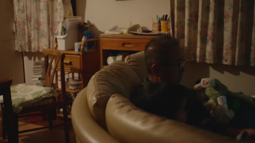 Father and son are inside of there home and sitting on the couch