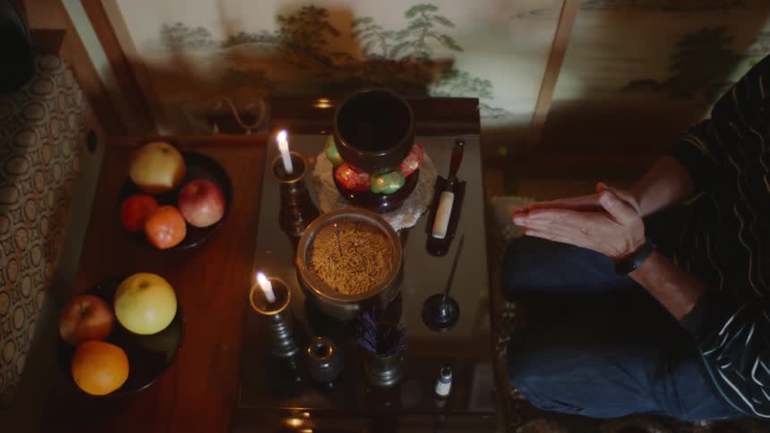Man places incense and rings bell on home shrine before praying