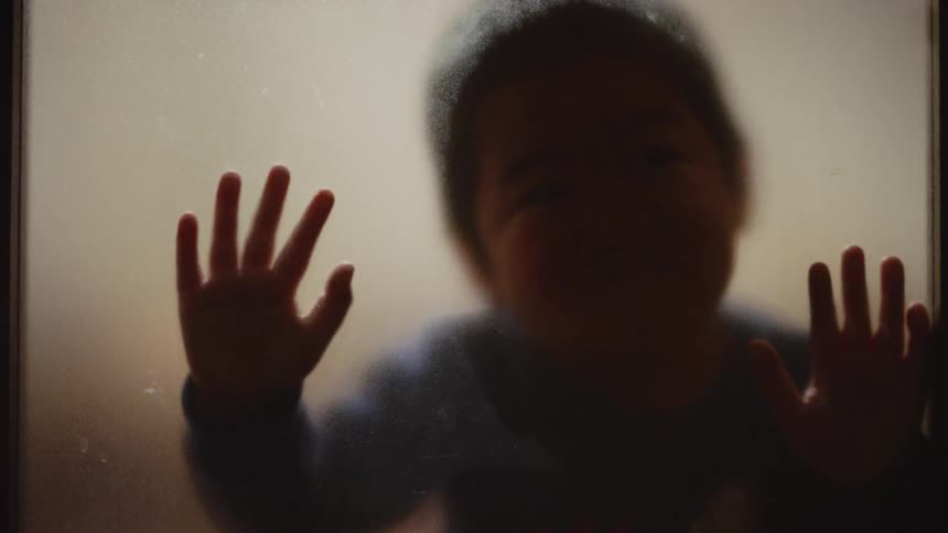 A face of a baby against a glass wall