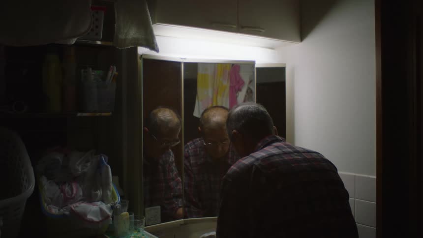 An older man is washing his hands inside of the bathroom
