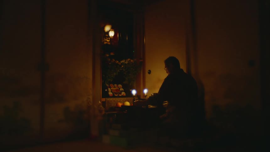 Man with glasses lights the candles in dark room