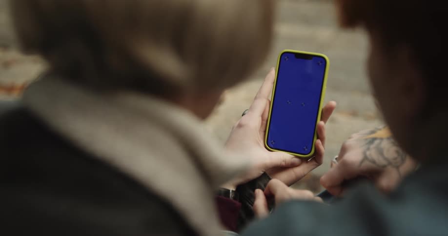 A couple is sitting down and is looking at there phone together