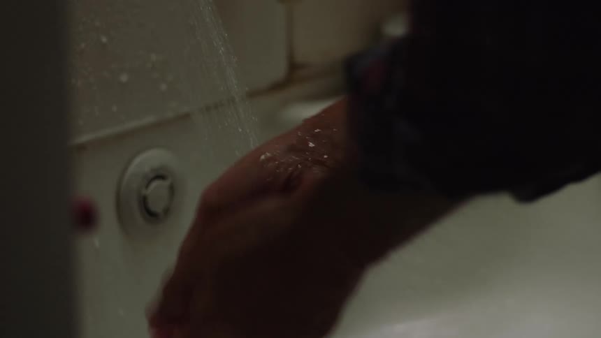 A person is washing their hands in a bathroom sink