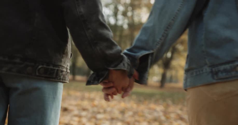Two people are holding hands and walking outdoors