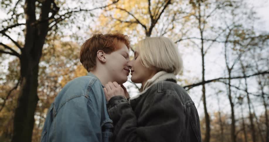 Lesbian couple walks down the road in public park making out