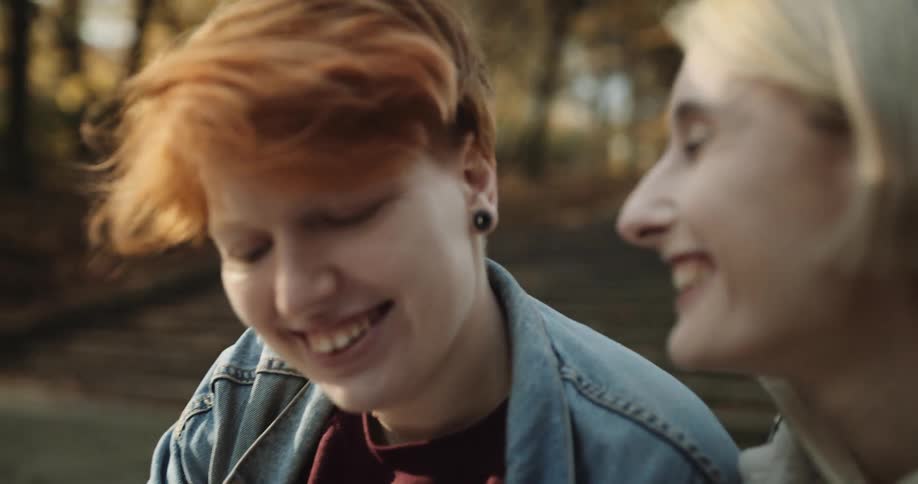 Two woman smiling and high fiving outside while looking at a smartphone