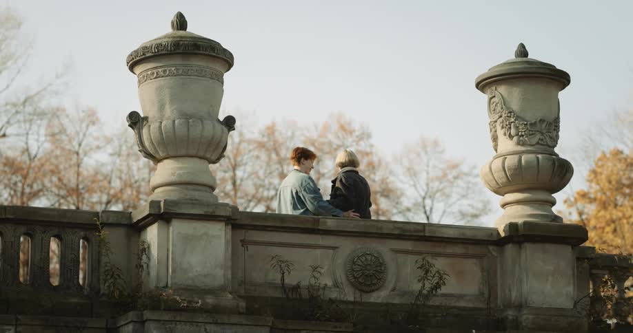 A young couple is outdoors taking pictures on there phone of being affectionate towards each other