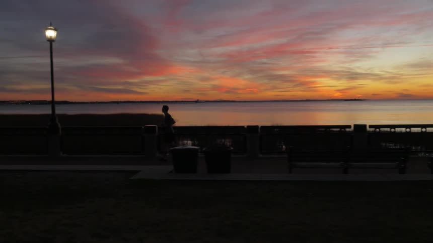 A person is jogging along the boardwalk at dawn