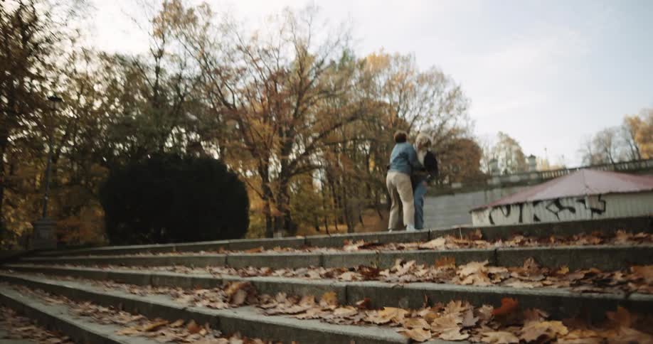 A couple running up stairs in a park while laughing and hugging