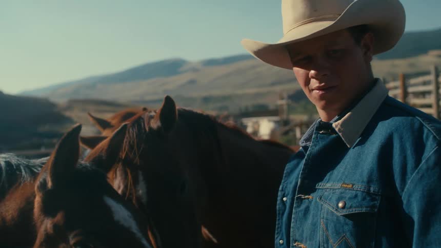 A man is standing at a ranch with his horses