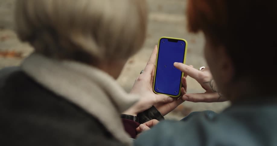 Two women looking at and swiping a smartphone screen