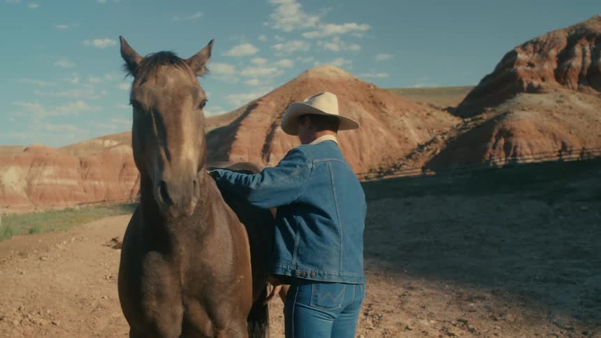 A man is standing outdoors with his horse