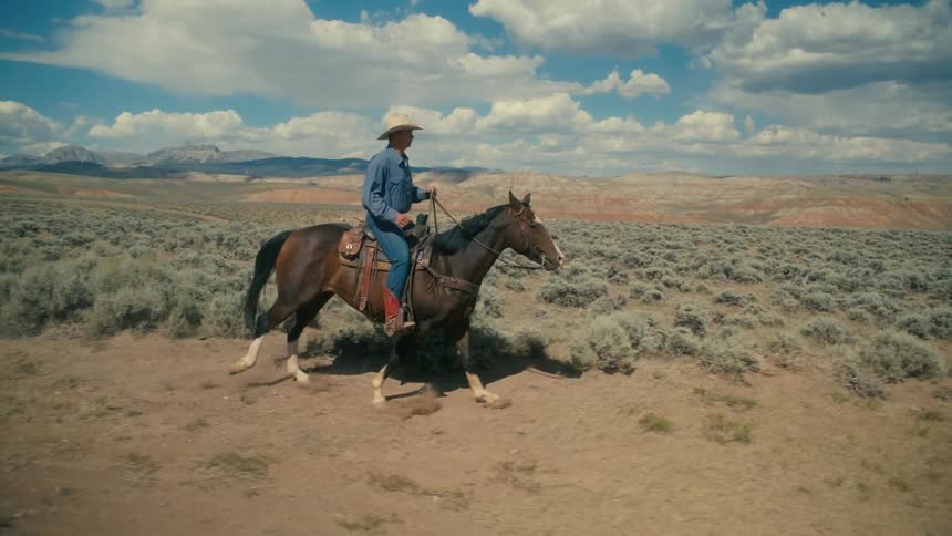 A man is riding a horse on a ranch in the middle of the day