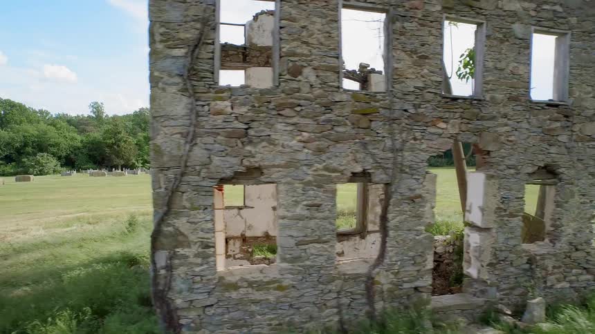A person rides a horse next to an broken building